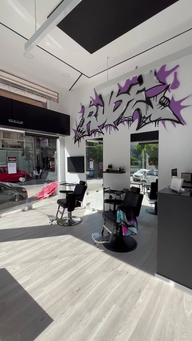 Ο μωβ γκράφιτι τοίχος του RUDE BARBERSHOP στο φως της μέρας