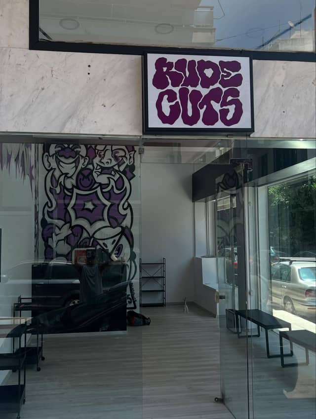 Η πρόσοψη του RUDE BARBERSHOP με την πινακίδα RUDE CUTS
